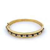 Gorgeous Sapphire & Diamond bangle bracelet in 14k Yellow Gold by Raymond Mazza. This hinged bangle is set with 10 square Blue Sapphires totaling 1.90ct and alternating with pairs of diamonds at 1.26ct. - Gaines Jewelers